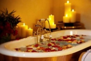 Photo of a bath with candles and rose petals