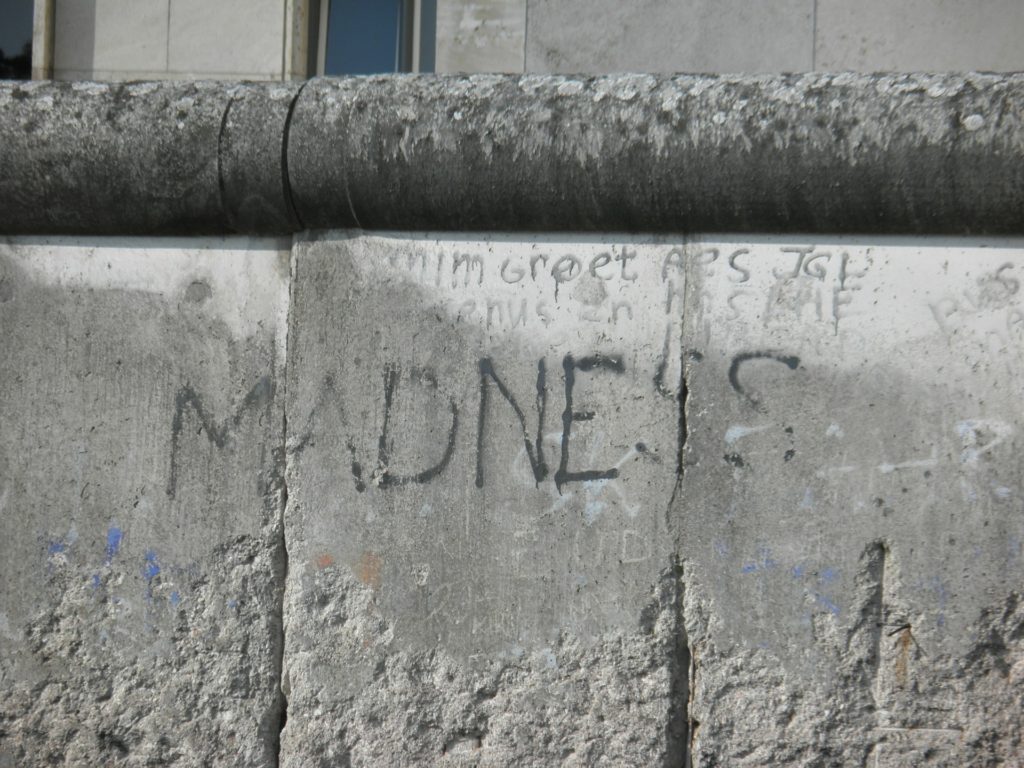 Wall with 'Madness' sprayed across it in fading letters
