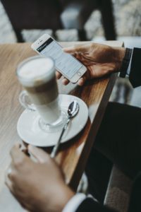 Man at a cafe table with his phone and a coffee
