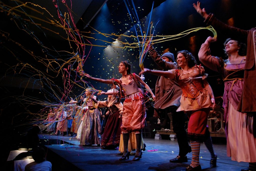 Actors on stage throwing streamers at audience