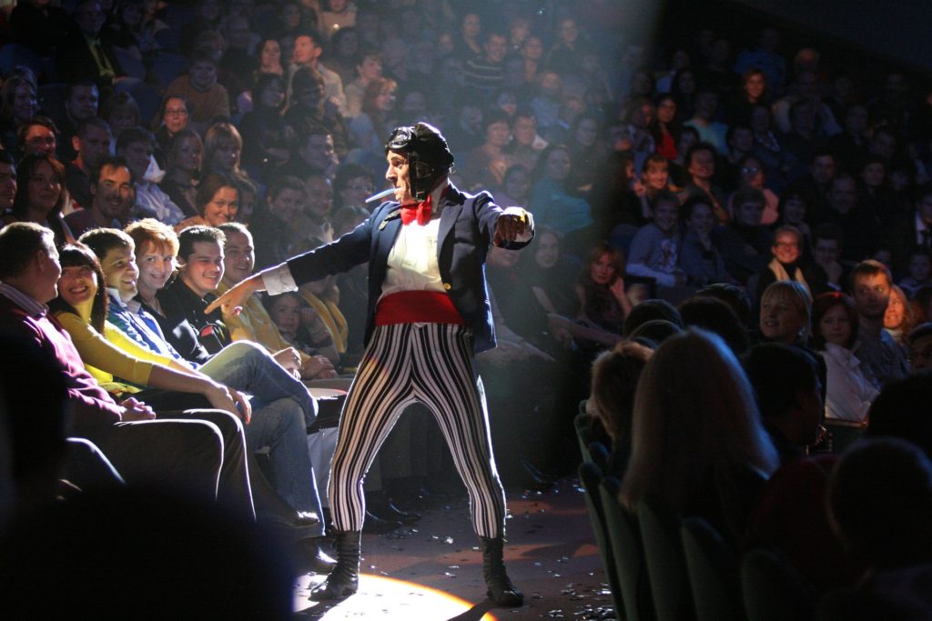 Man in a clown costume dancing around an audience