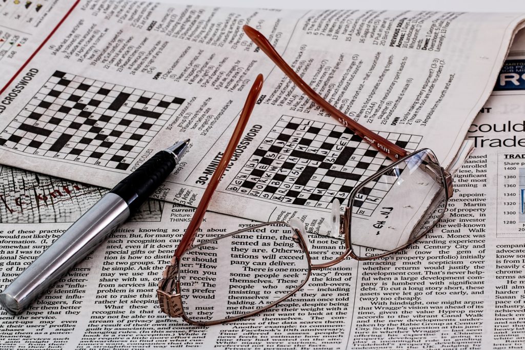 Crossword puzzle with glasses and pen lying on top