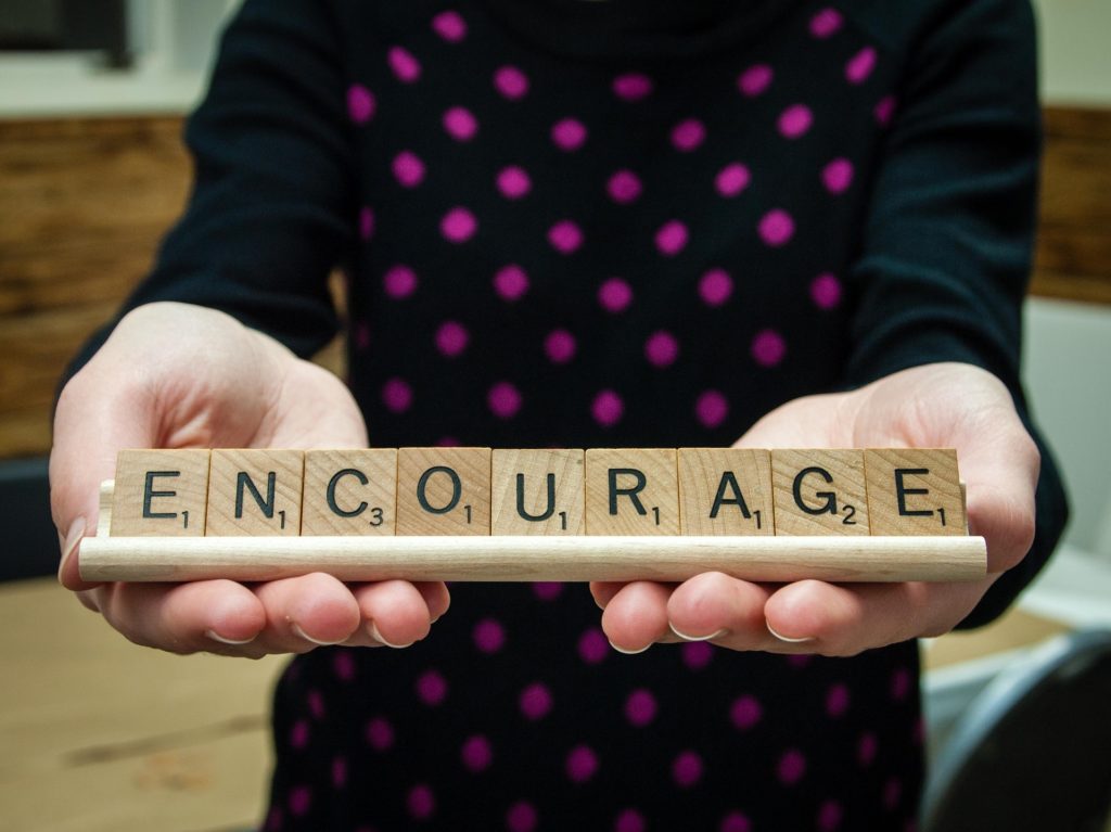 Scrabble tiles on a rack spelling out 'encourage'