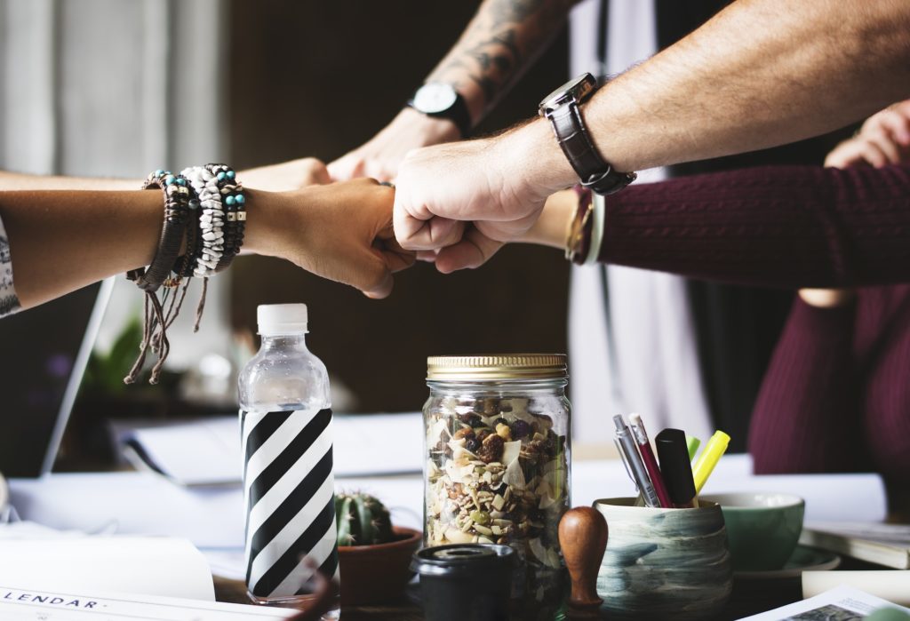 Team of people knocking fists over a table