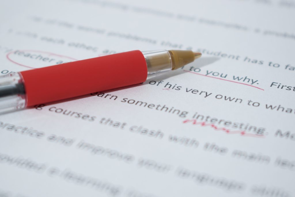 Red pen resting on annotated essay