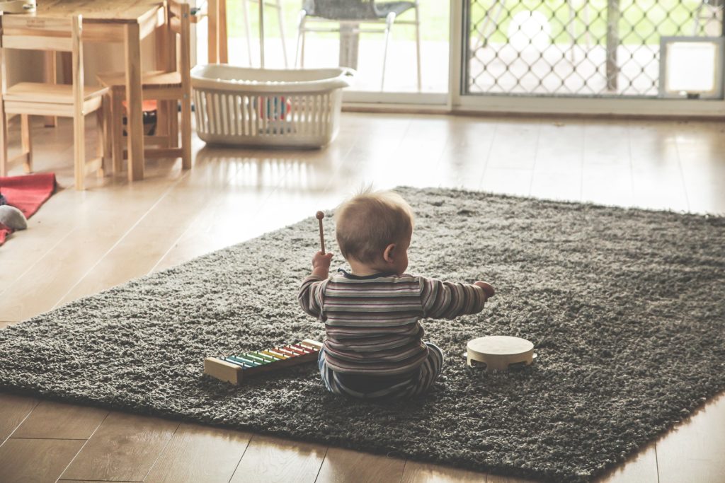 Toddler on a mat with a xylophone and tambourine